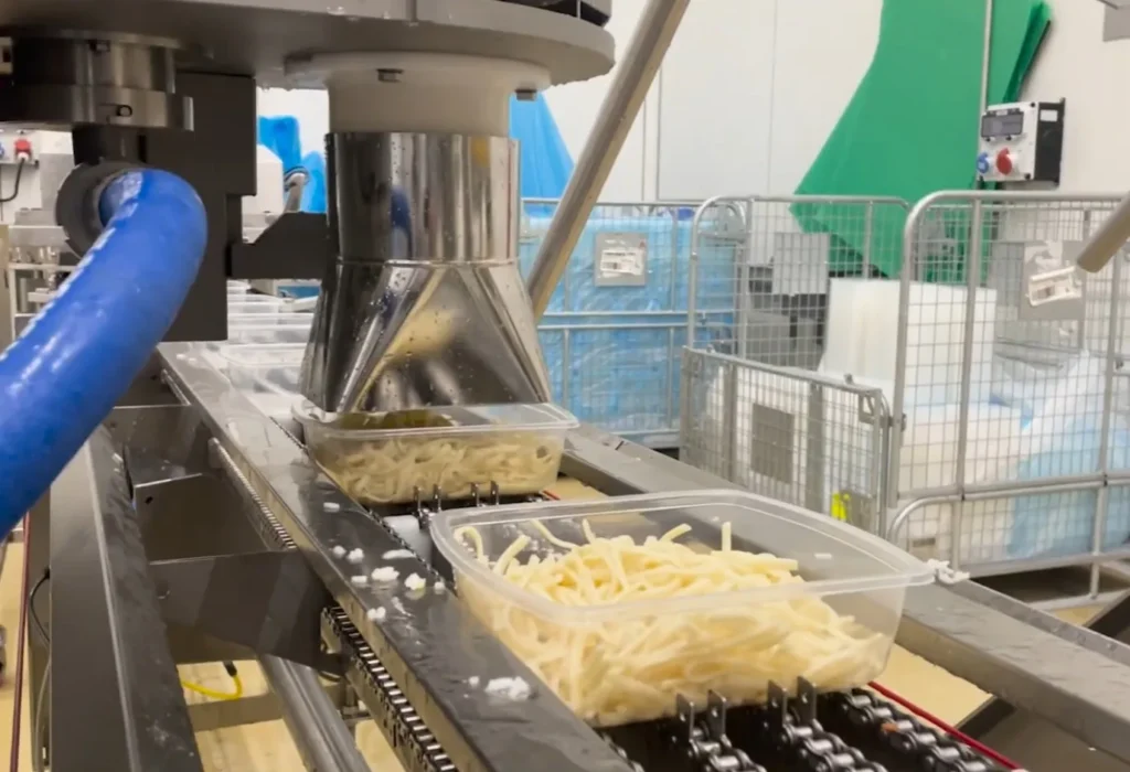 SD-Dosiermaschine zur automatischen Dosierung von Spaghetti in Einwegschalen auf einem Förderband.